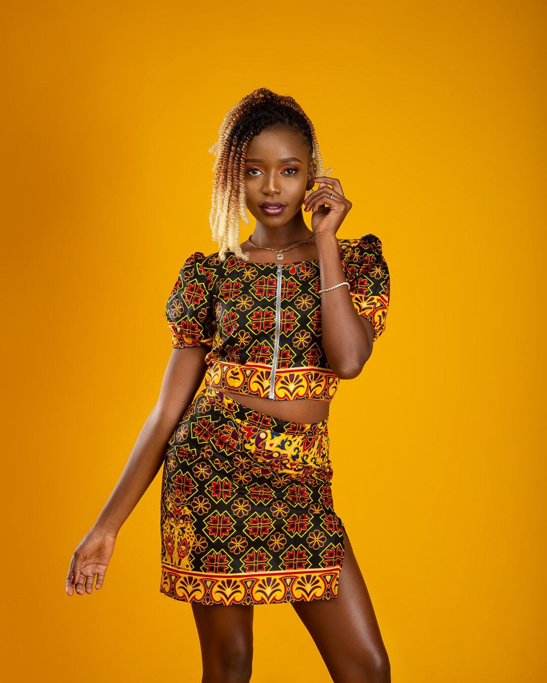 Becky Sangolo in an African print two-piece outfit against a bright yellow backdrop