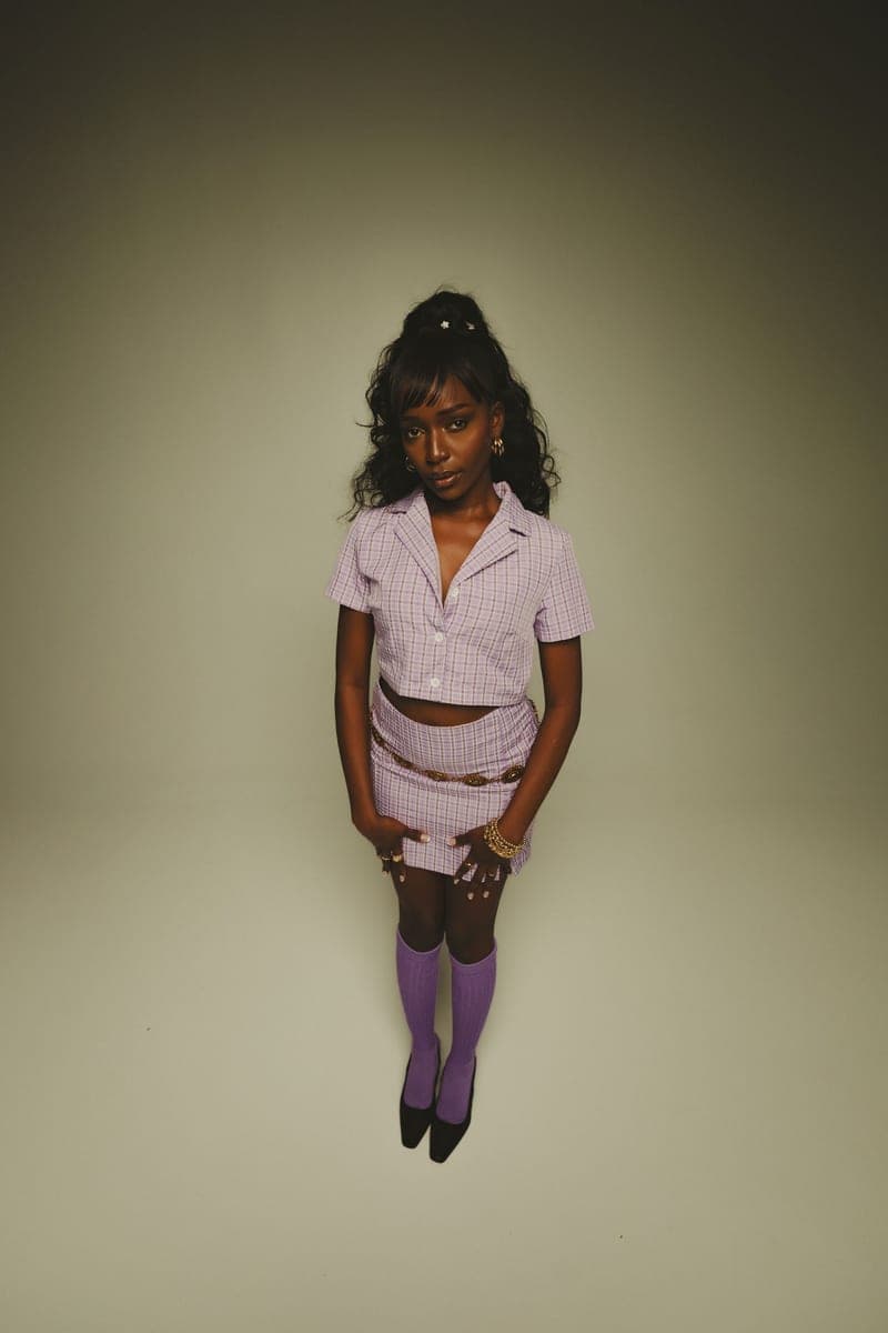 Becky Sangolo standing in a lilac plaid crop top and skirt with a gold chain belt