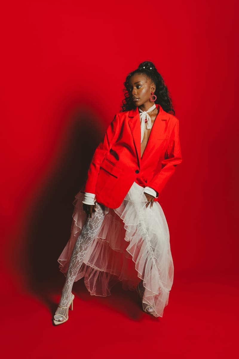 Becky Sangolo in a red blazer and white ruffled tulle skirt against a bold red backdrop